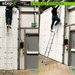 Man ascending 'Step-It' ladder by rackit direct inside an industrial space, demonstrating its 4.1m fully extended height. The ladder stands next to an exit door with an emergency push-to-open sign.